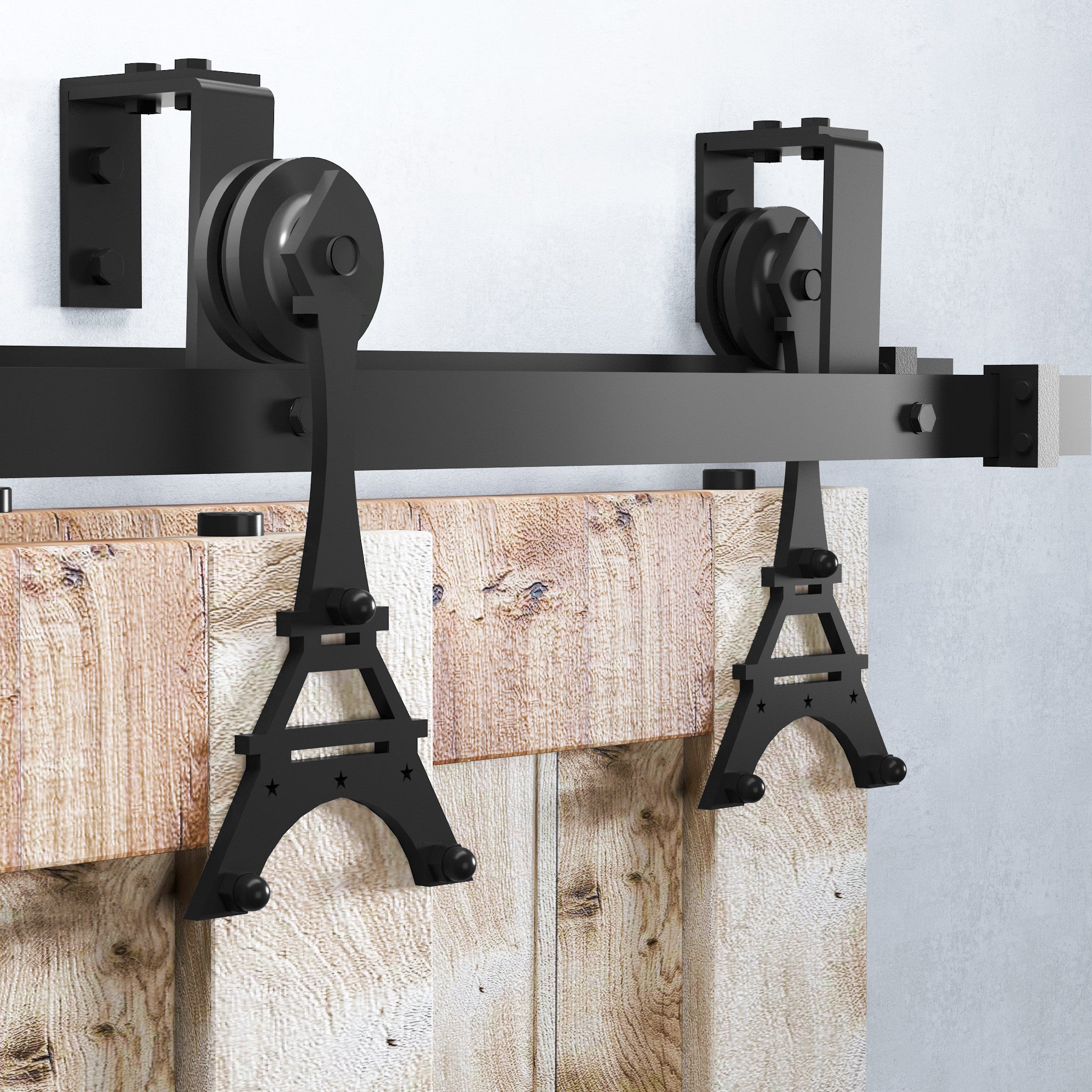 Close-up view of the Homacer Eiffel barn door kit featuring black steel Eiffel-style hangers and rollers mounted on a sturdy bypass track above rustic wood barn doors.